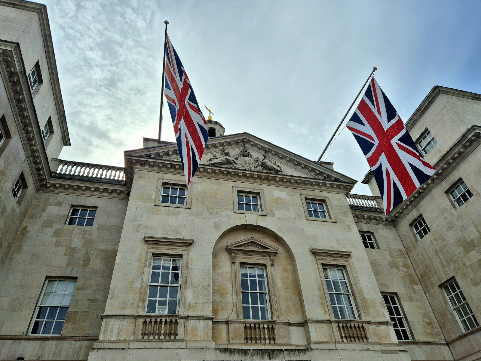 Two union jack flags flying on a classical building