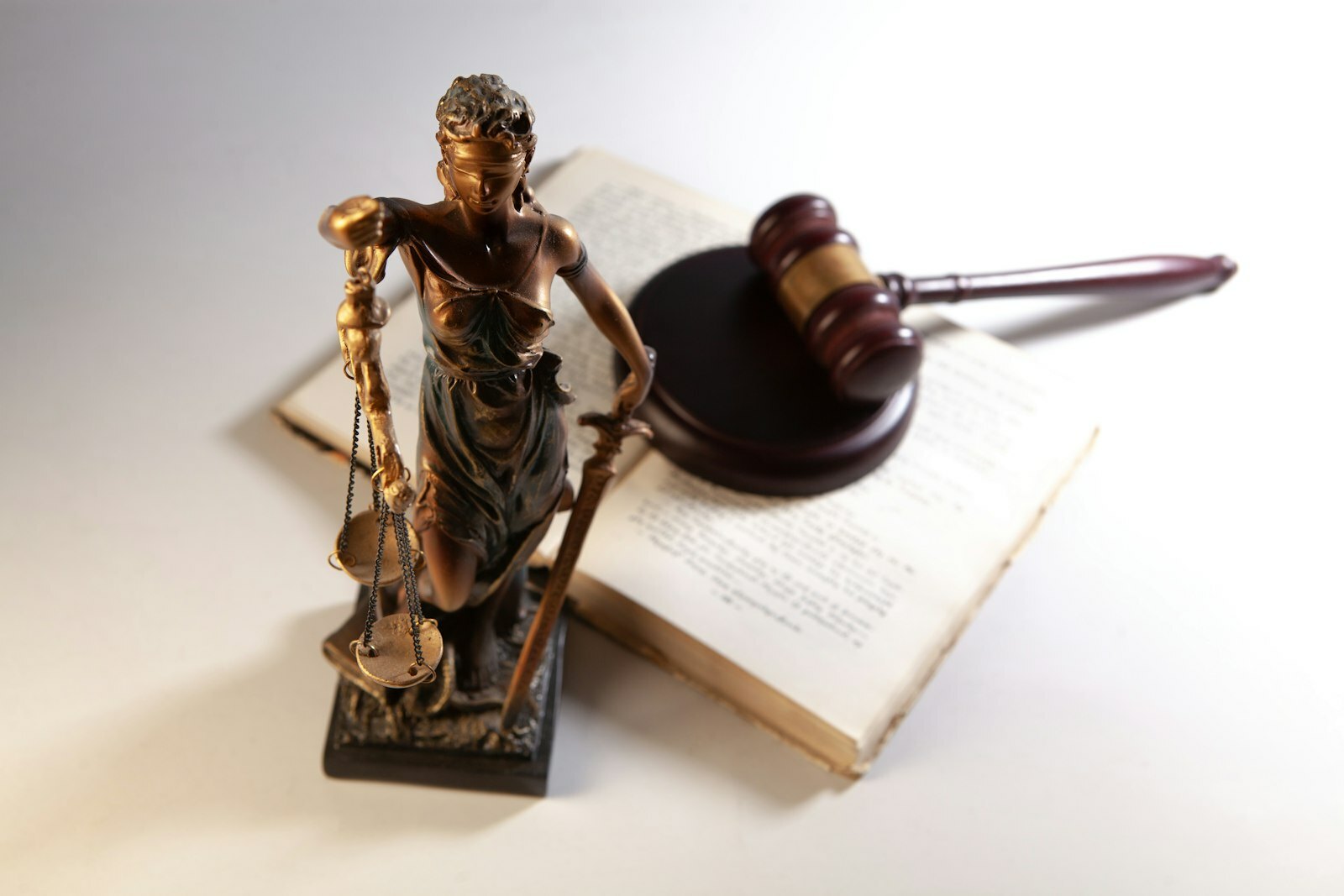 Statue of justice, gavel, and open book on table