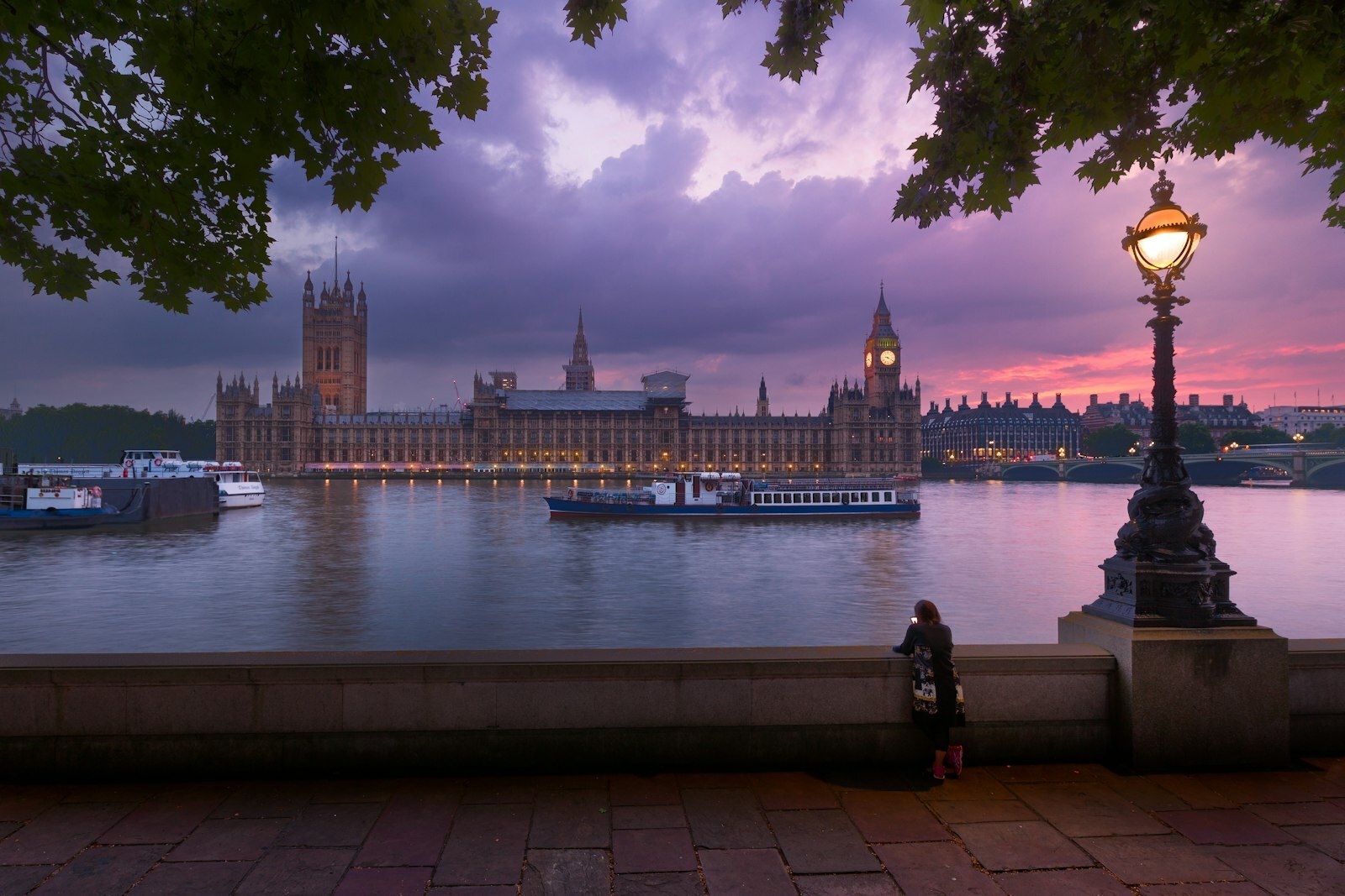 A person leaning on a wall overlooking the River Thames and Big Ben in London